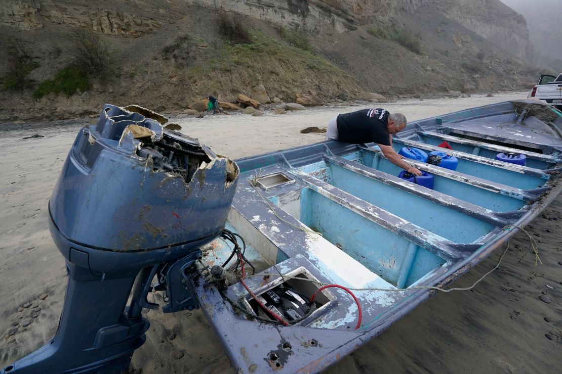 Boat salvager Robert Butler picks up a canister Sunday in one of the two boats sitting on Black's Beach.