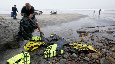 Boat salvager Robert Butler picks up life preservers in front of one of two boats sitting on Blacks Beach, Sunday, March 12, 2023, in San Diego.