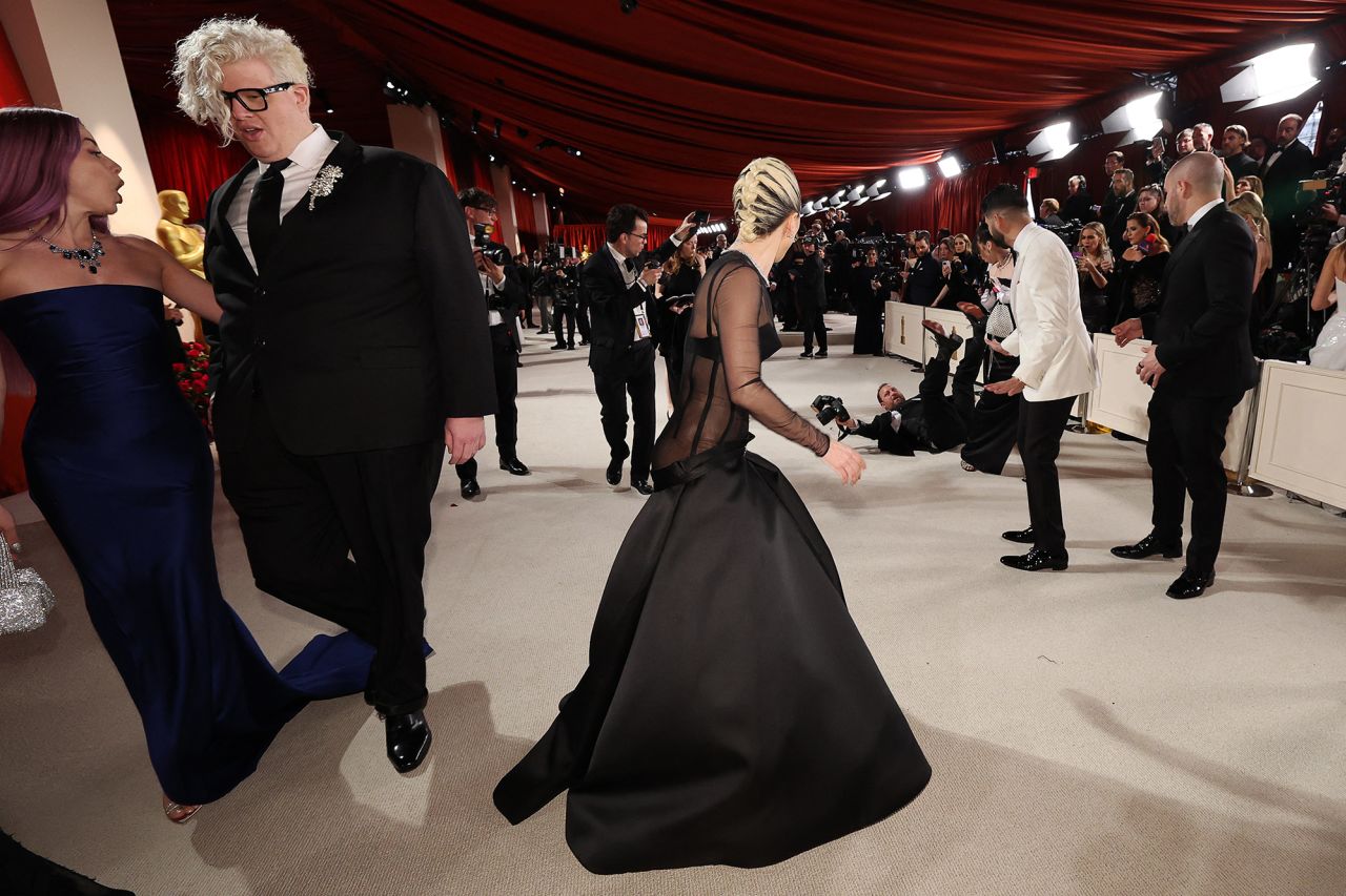 Lady Gaga looks back at a photographer who fell on the champagne-colored red carpet ahead of the Academy Awards on Sunday, March 12. The singer went back to help the man up.
