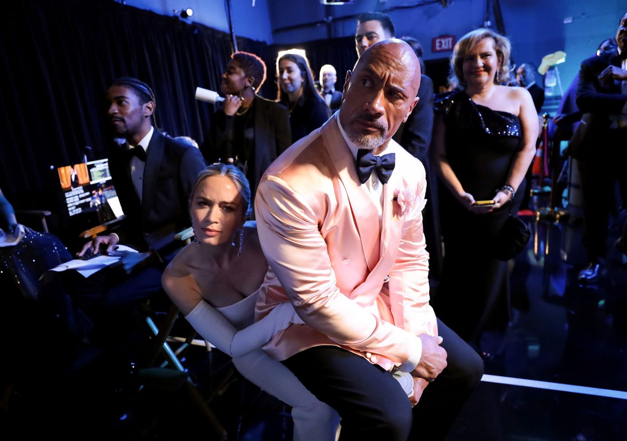 Dwayne Johnson sits on Emily Blunt's lap backstage. The two presented an award together during the show.
