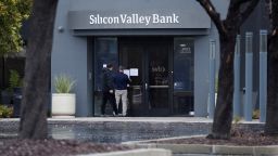 A man puts a sign on the door of the Silicon Valley Bank as an onlooker watches at the bank's headquarters in Santa Clara, California, U.S. March 10, 2023. 