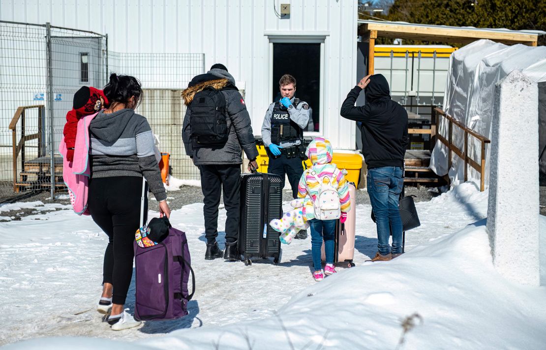 An officer speaks to migrants as they arrive at the Roxham Road border crossing in Roxham, Quebec, Canada, on March 3, 2023.