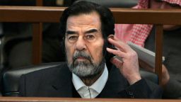 Iraqi dictator Saddam Hussein listens to a translation through headset during his December 2006 trial for genocide in Baghdad, 
