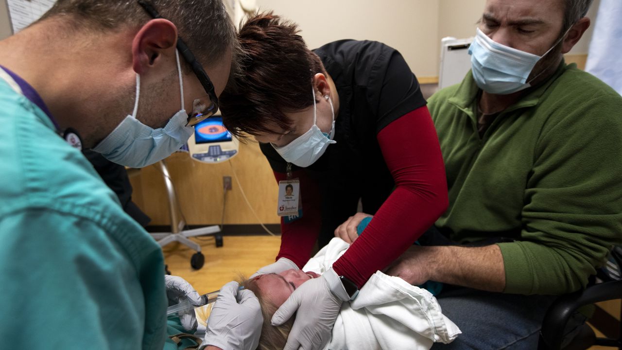 Steve Inglish, left, and registered nurse Nikole Hoggarth, middle, help a father with his daughter, who fell and required stiches, inside the emergency department at Jamestown Regional Medical Center in rural North Dakota in 2020.
