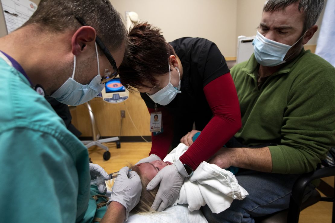 Steve Inglish, left, and registered nurse Nikole Hoggarth, middle, help a father with his daughter, who fell and required stiches, inside the emergency department at Jamestown Regional Medical Center in rural North Dakota in 2020.