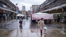 People out and about in the rain along the market area on Watney Street in Shadwell on 8th March 2023 in London, United Kingdom. 