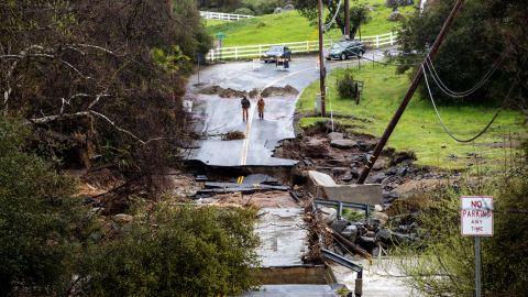 Los residentes observan los daños después de que el río Tulare, de rápido movimiento e hinchado, derrumbara partes de Globe Drive el 14 de marzo de 2023 en Springville, California. 