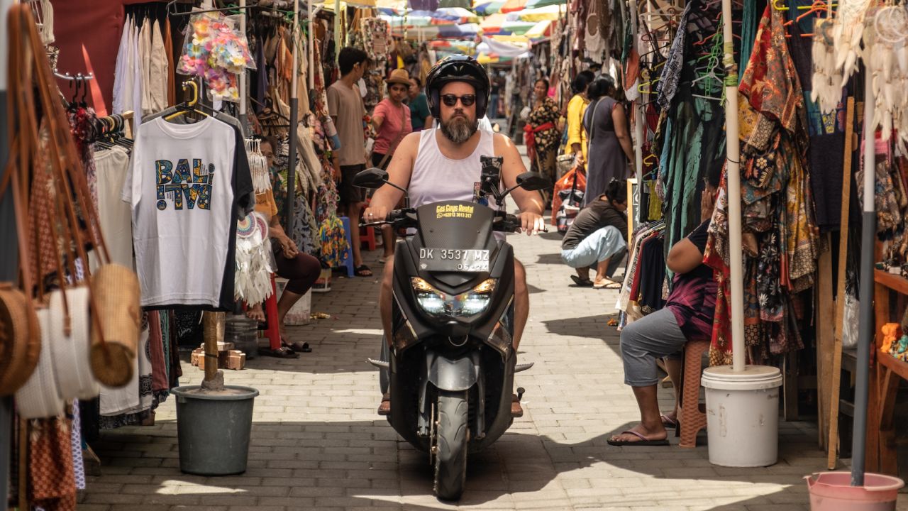 A tourist rides a motorbike through Ubud street art market in Bali in December 2022. 