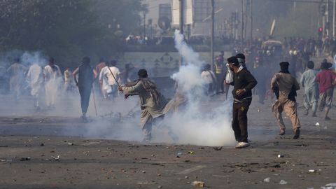 Imran Khan backers throw stones at riot police officers firing tear gas on March 15, 2023.