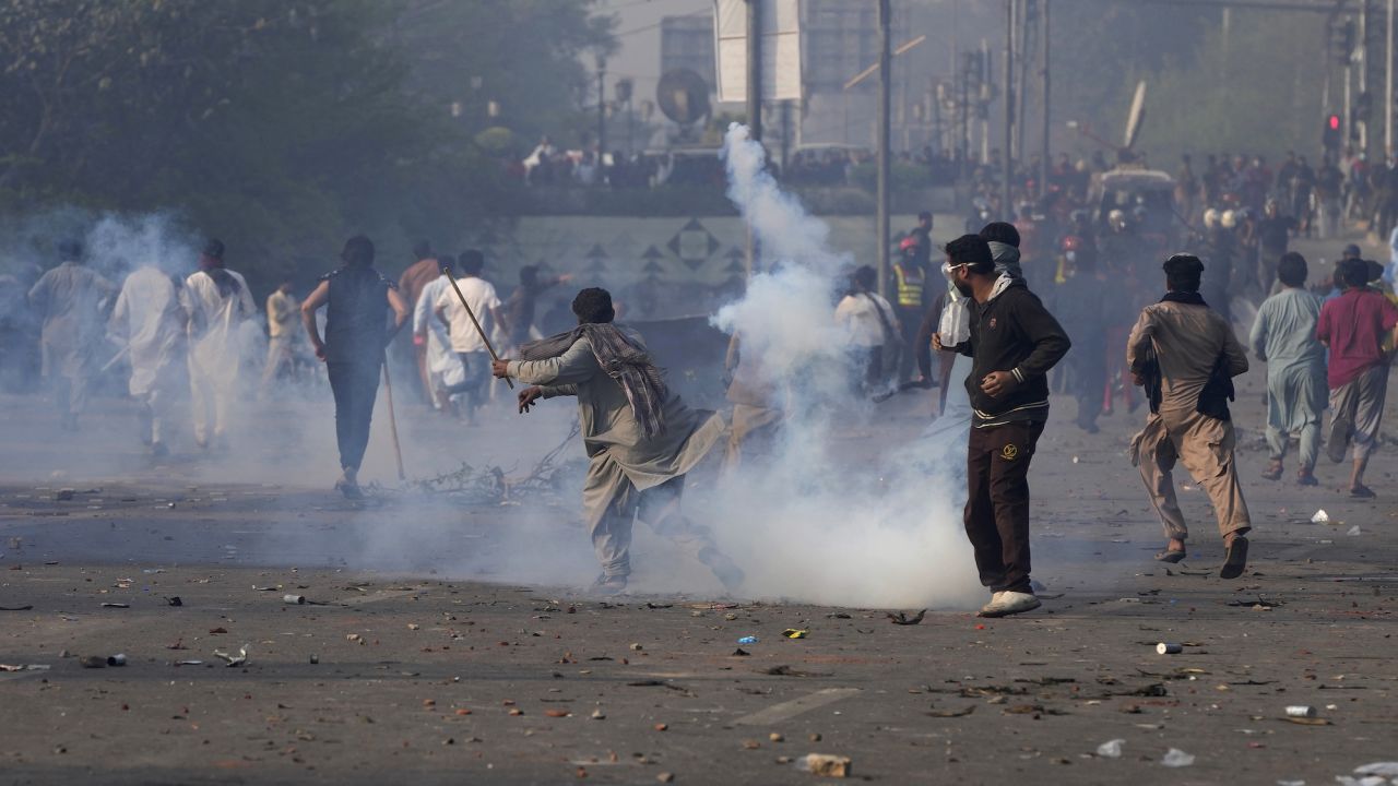 Imran Khan backers throw stones at riot police officers firing tear gas on Wednesday.