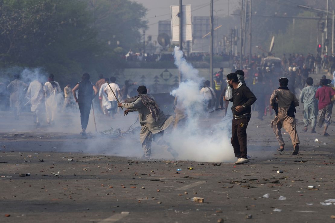 Imran Khan backers throw stones at riot police officers firing tear gas on Wednesday.