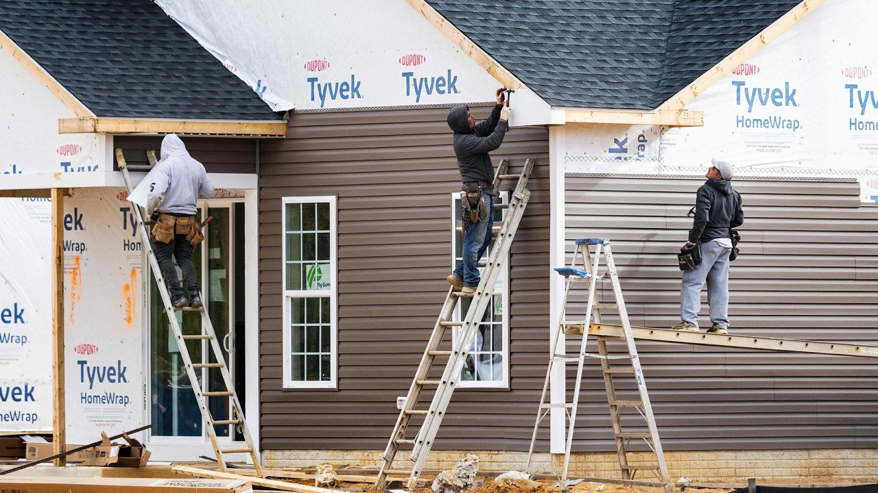 Workers attach siding to a house at a new home construction site in Trappe, Maryland.
