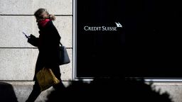 A woman is seen in silhouette walking past a branch of Switzerland's Credit Suisse bank in Vevey, western Switzerland, on March 15, 2023. Credit Suisse shares were in freefall on March 15, 2023 on the Swiss stock exchange, plunging 20 percent in morning trading to historic new record lows. 