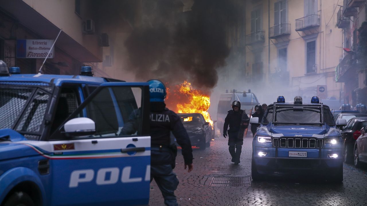 Supporters of Eitracht Frankfurt set a police car on fire as they clash with police.