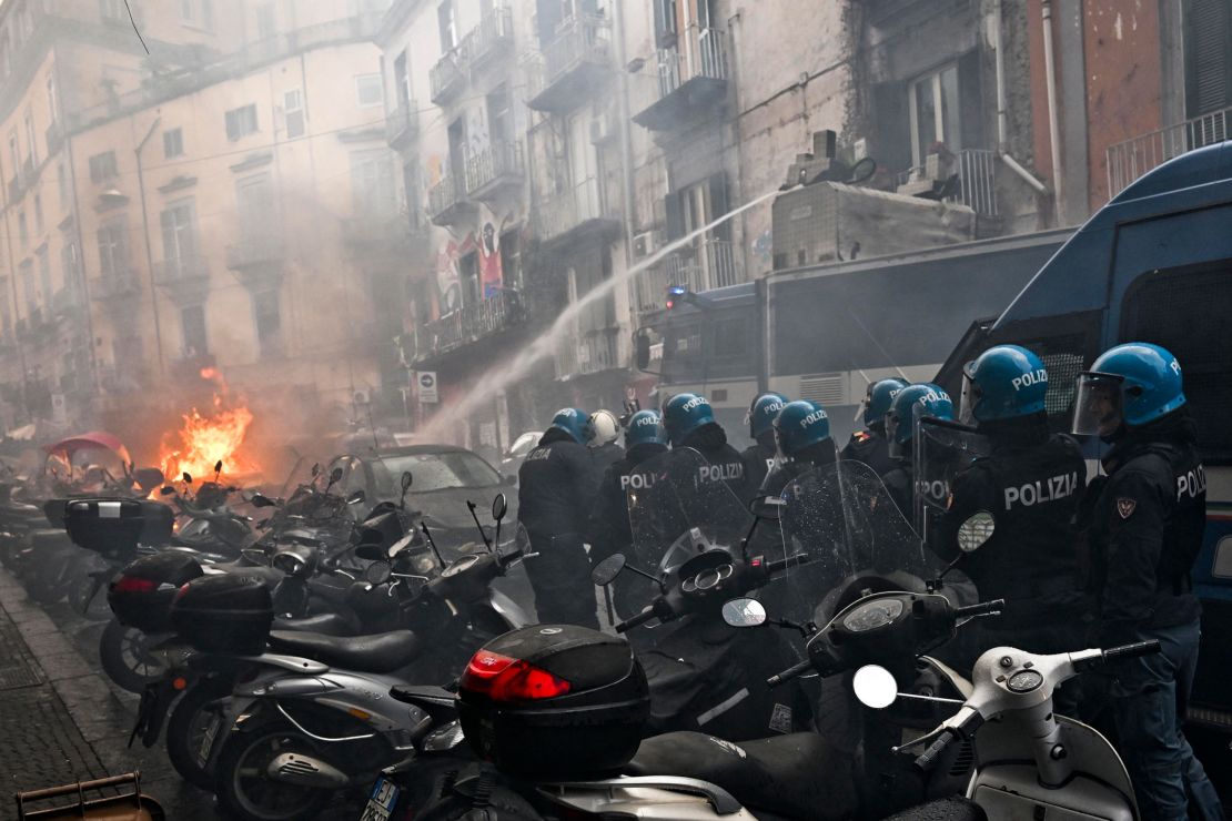 Anti-riot police move beside a truck, extinguishing the blaze of a police car.