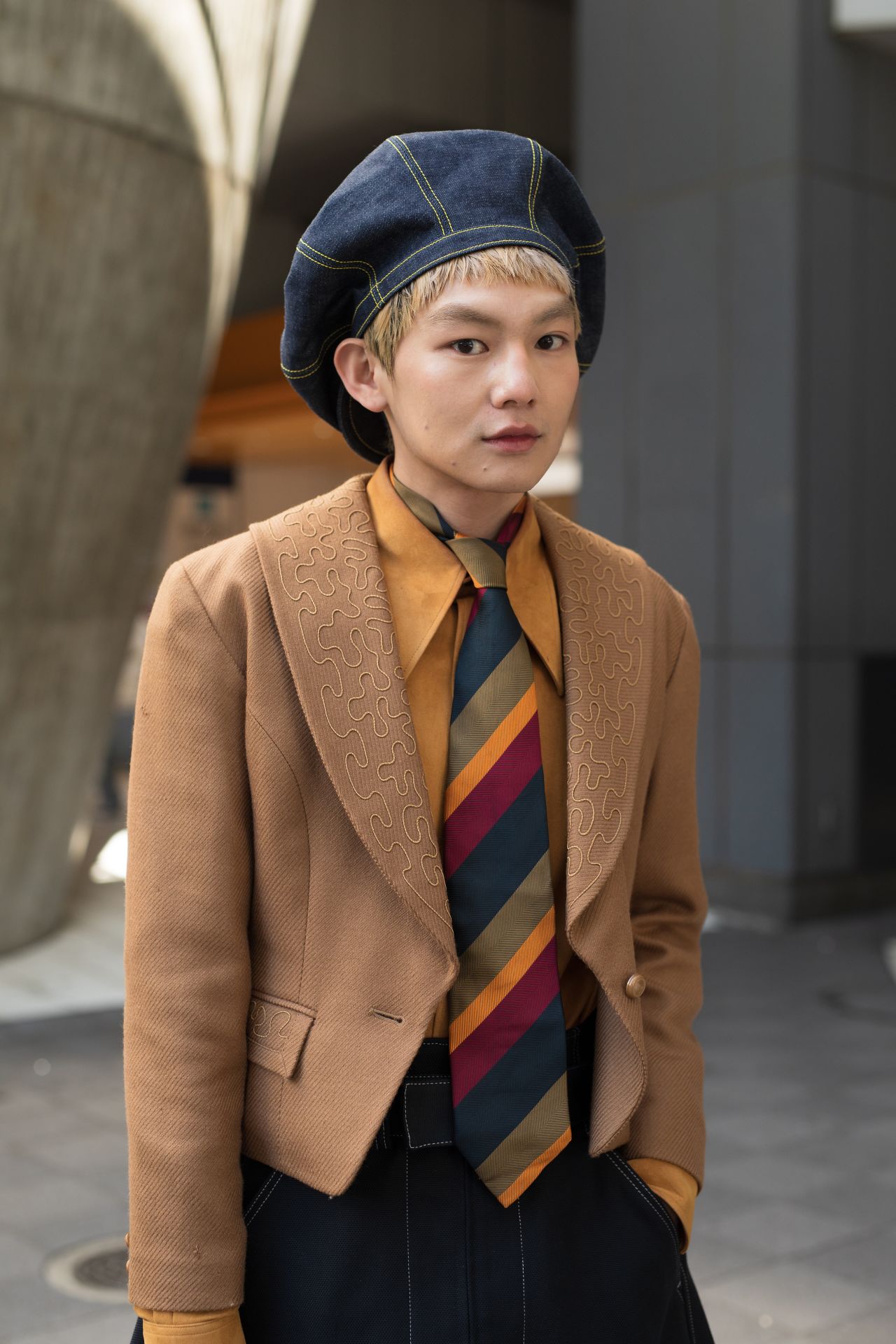 An attendee at Seivson fashion festival is seen wearing a vintage striped tie, a denim beret and an embellished tan blazer.