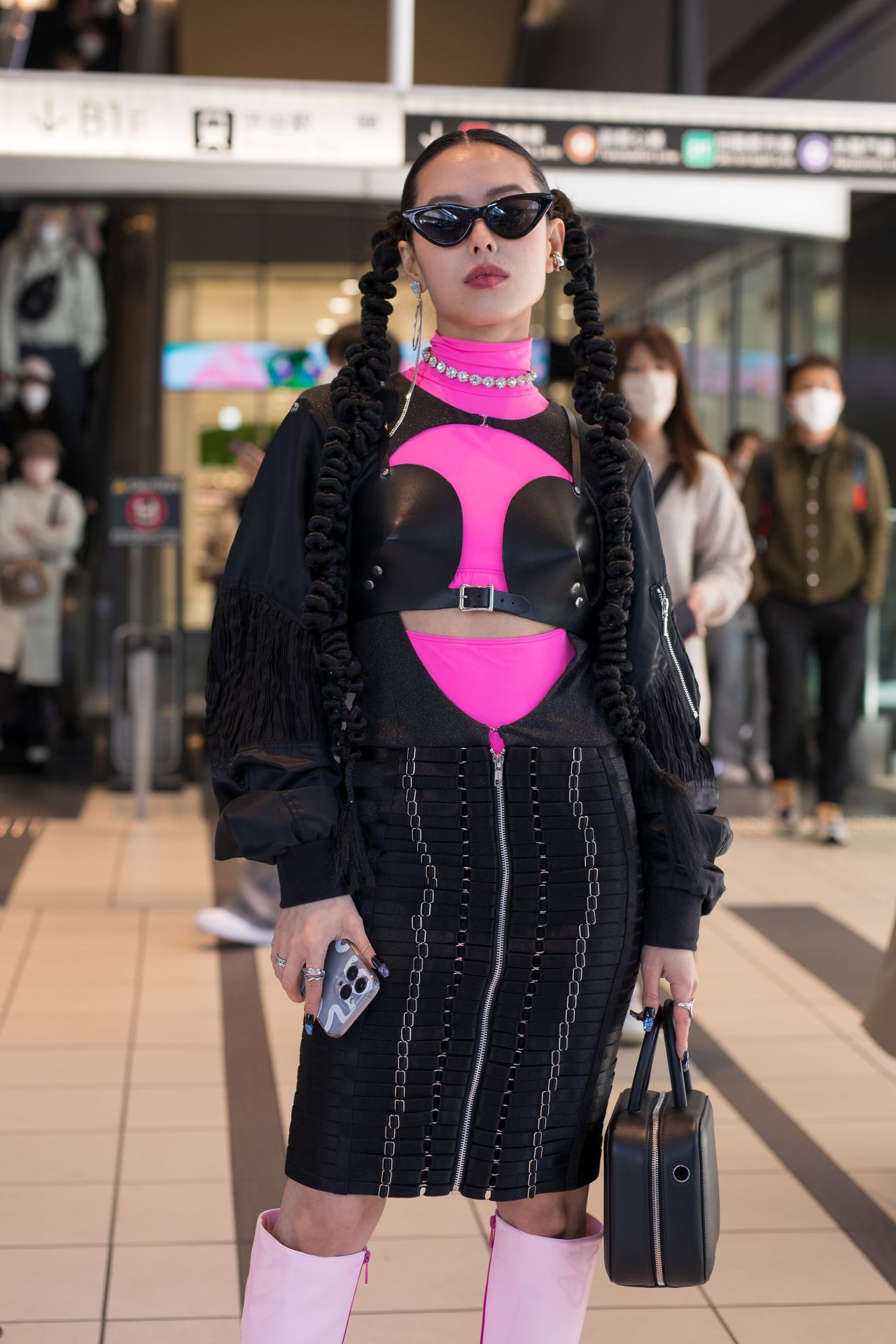 An eye-catching black and hot pink ensemble worn with cat-eye sunglasses, silver jewelry, and knee-high boots. 