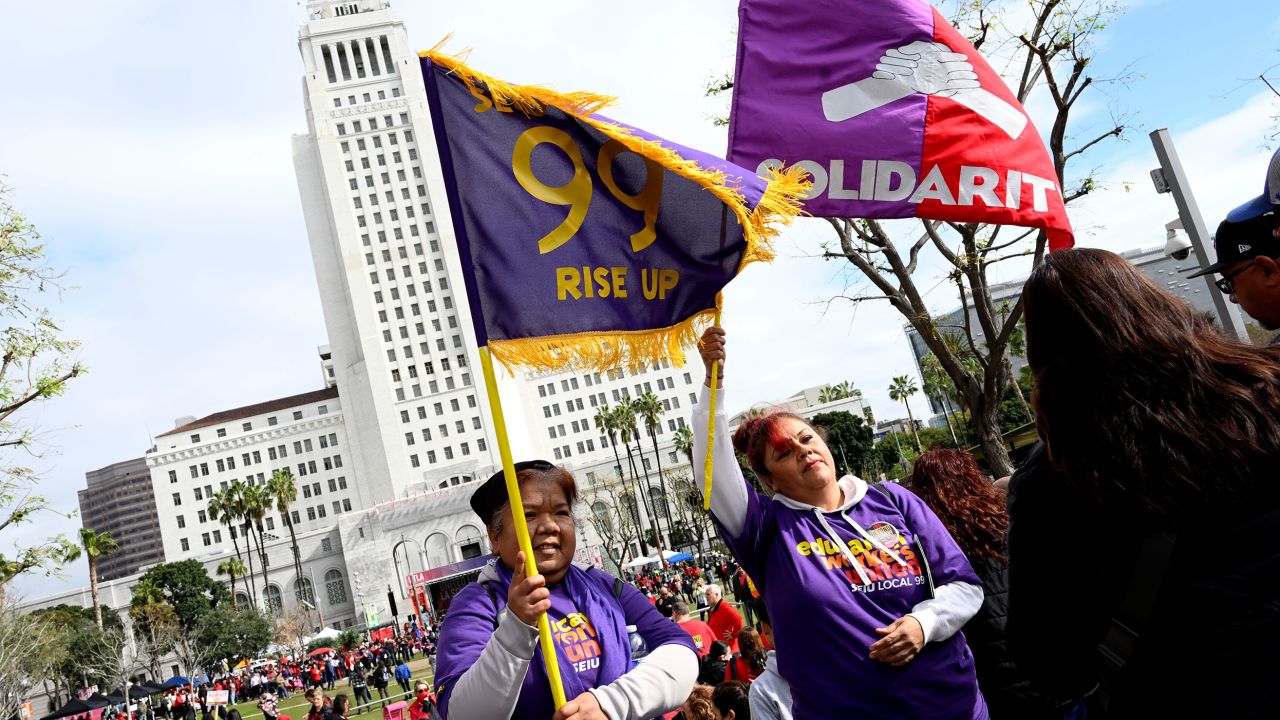 Members of the school workers union hold up flags as thousands rally Wednesday in front of Los Angeles City Hall.