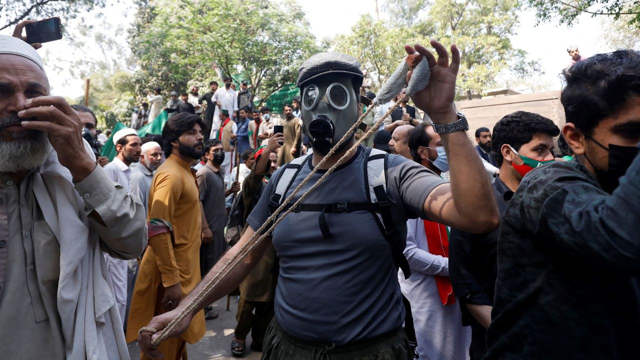 A supporter of Imran Khan poses with a slingshot as he and other supporters gather outside the former prime minister's home in Lahore, on March 16, 2023.