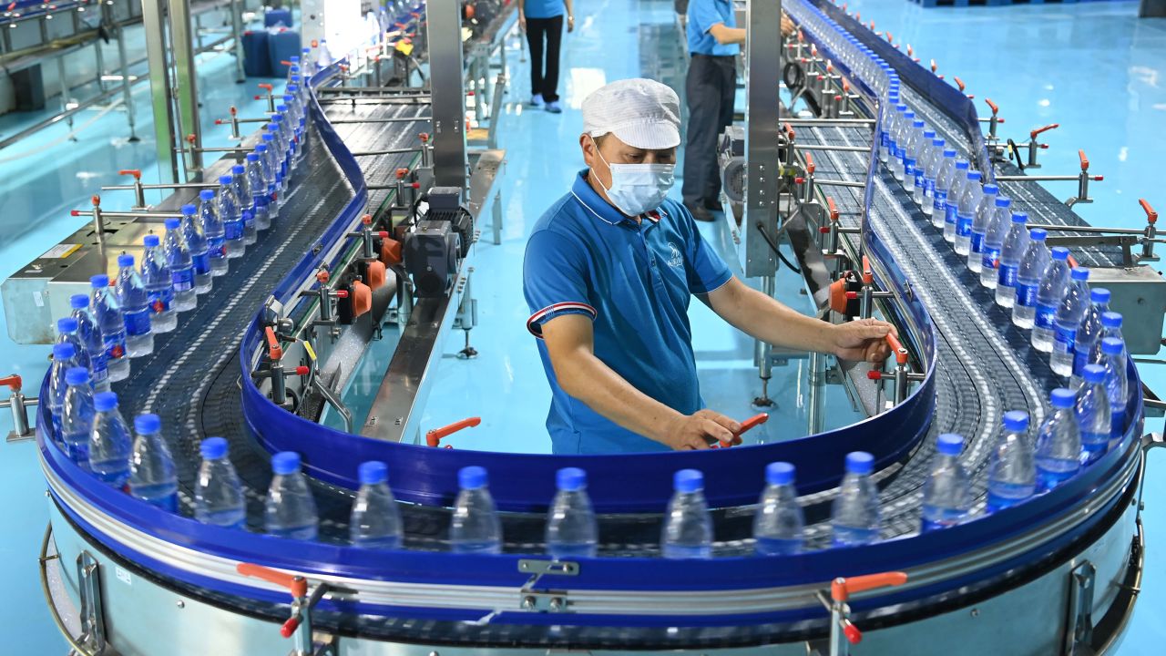Werknemers werken in 2022 aan de productielijn van plastic flessenwater in een fabriek in Yichun, in de provincie Jiangxi in China.