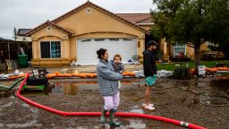 Madisyn Liles holding Luka,1, watches with her husband Keylan as two pumps continue to work throughout the day to remove flood water from their home after  Tuesday nights heavy rains on March 15, 2023 in Woodlake, California. 
