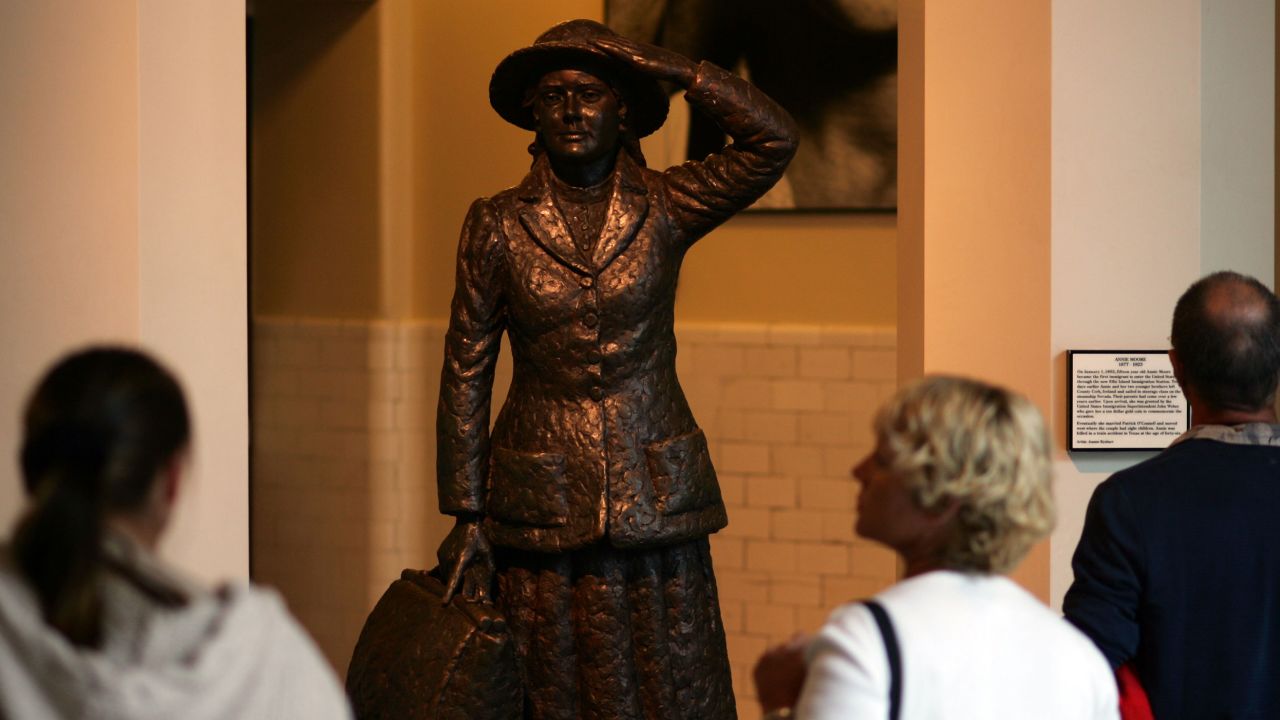 Visitors at Ellis Island in 2006 look at a statue that depicts Annie Moore, holding her hat in the harbor breeze. Ireland's president unveiled the statue in 1993.