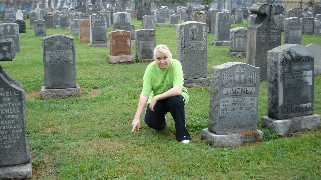 For decades after her death, Annie Moore's grave at Calvary Cemetery in Queens, New York, was unmarked. In this photo, genealogist Megan Smolenyak points to the grave the day she first visited it in 2006. Some of Moore's descendants helped lead a fundraising efforts for a gravestone, which was unveiled at the site in 2008.