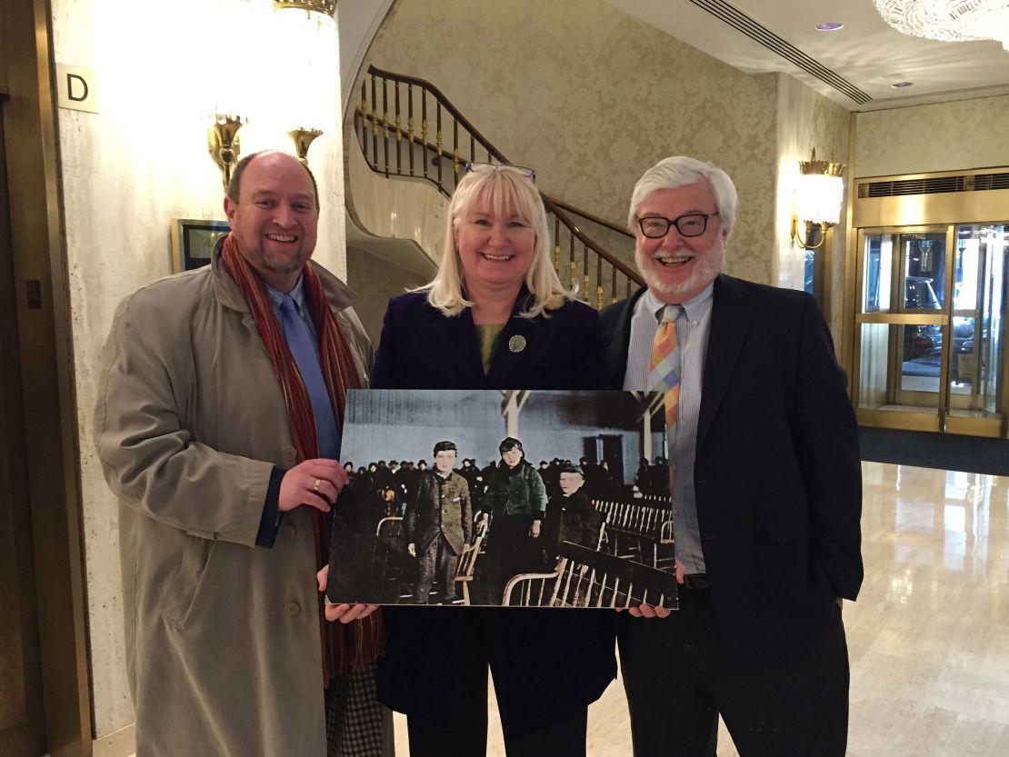 In 2016, genealogist Megan Smolenyak introduced the American and Irish branches of Annie Moore's descendants for the first time in New York. Here she stands with Paul Linehan of Kildare, Ireland, whose great grandfather was Moore's first cousin, and Michael Shulman of Chevy Chase, Maryland, whose grandfather was Moore's brother. They are holding a photo they believe shows Moore and her brothers after they arrived at Ellis Island.