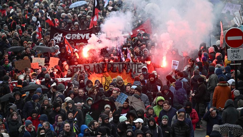 TOPSHOT - Demonstrators march with banners and flares during a rally called by French trade unions in Nantes, western France on January 19, 2023, as workers go on strike over the French President's plan to raise the legal retirement age from 62 to 64.. - A day of strikes and protests kicked off in France on January 19, set to disrupt transport and schooling across the country in a trial for the government as workers oppose a deeply unpopular pensions overhaul. (Photo by LOIC VENANCE / AFP) (Photo by LOIC VENANCE/AFP via Getty Images)