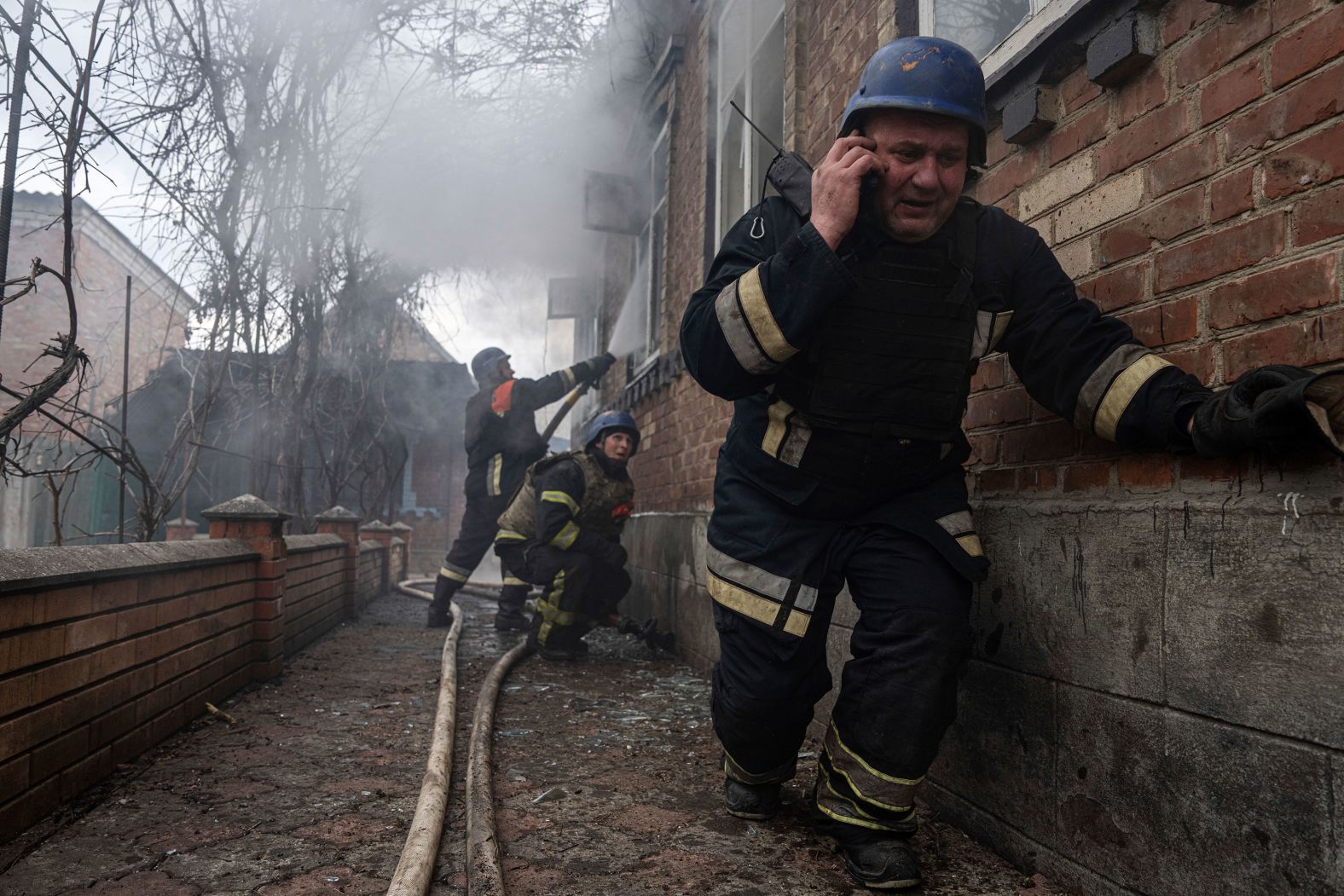 A rescue worker speaks on the phone while other members of his team put out a house fire caused by Russian shelling in Kostiantynivka, Ukraine, on Friday, March 10.