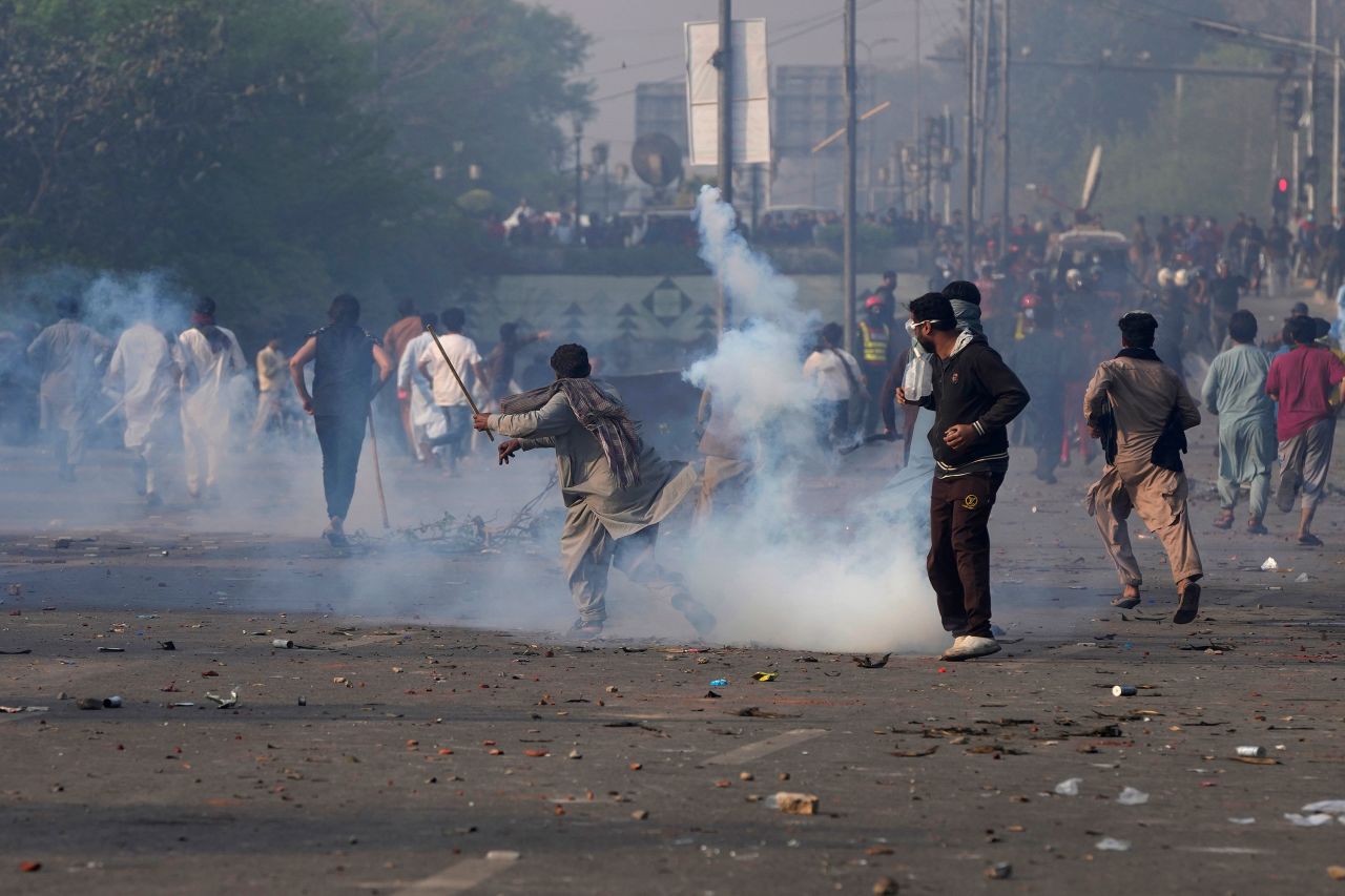 Supporters of former Pakistani Prime Minister Imran Khan throw stones toward riot police officers firing tear gas to disperse them in Lahore, Pakistan, on Wednesday, March 15. <a href=