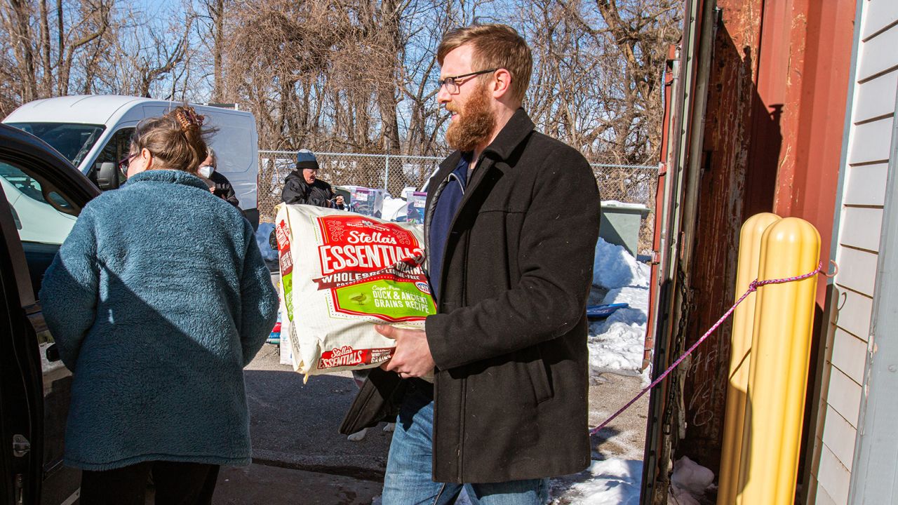 Josh Fiala, Animal Rescue League of Iowa's Pet Support Services Manager, aiuta a caricare cibo per animali domestici in un veicolo durante una dispensa di alimenti per animali domestici nel gennaio 2022. 
