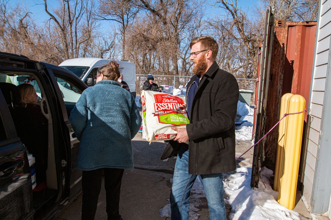 Josh Fiala, Animal Rescue League of Iowa's Pet Support Services Manager, helps load pet food into a vehicle during a Pet Food Pantry in January 2022. 