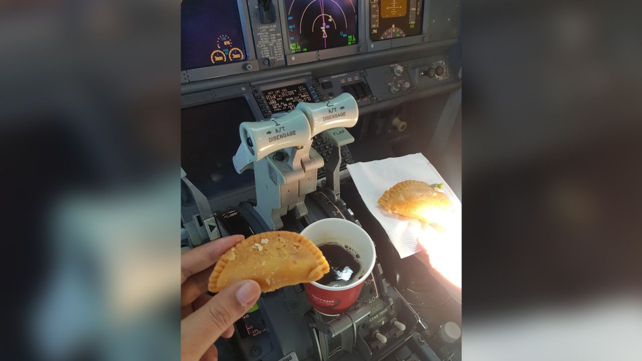 La foto compartida el 14 de marzo de 2023 muestra a dos pilotos tomando una bebida caliente y un pastel tradicional indio dentro de la cabina del avión.
