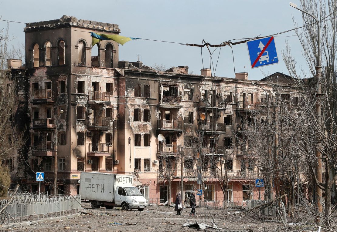 Local residents walk along a street next to a building damaged during the Ukraine-Russia conflict in the southern port city of Mariupol, Ukraine, on April 3, 2022.