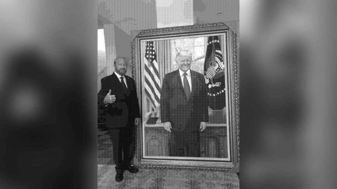 In this undated photo from an email obtained by CNN, US Ambassador to El Salvador Ronald Johnson stands with a painting of former President Donald Trump at the US Embassy in El Salvador.