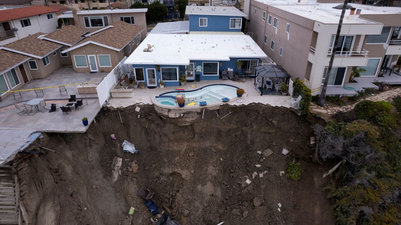A backyard pool is left hanging on a cliffside Thursday after torrential rain hit the beachfront town of San Clemente, California.