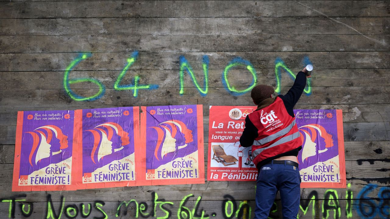 An anti-pension reform demonstrator writes "64-non" on part of a roadblock to the the oil terminals at the Total Energies refinery during a protest in Donges, western France on Friday. 