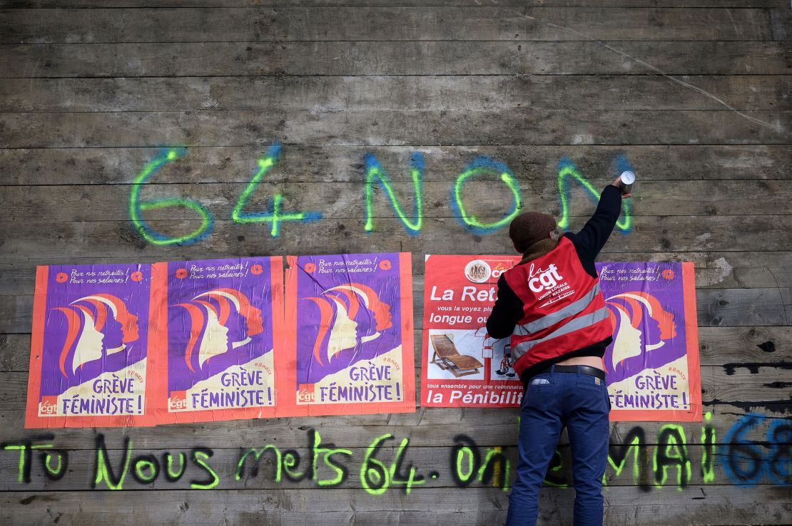 An anti-pension reform demonstrator writes "64-non" on part of a roadblock to the the oil terminals at the Total Energies refinery during a protest in Donges, western France on Friday. 