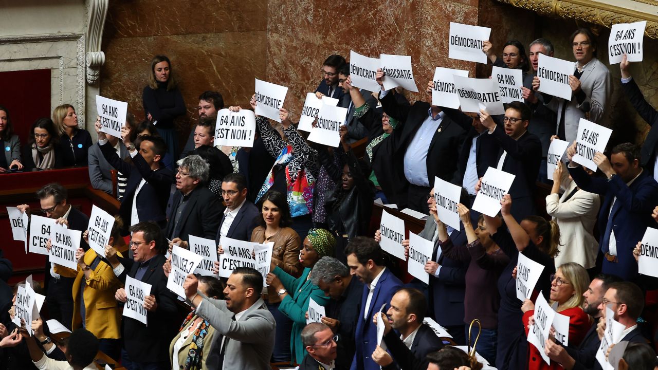 Los parlamentarios de la coalición de izquierda NUPES (Unión Social y Ecológica del Nuevo Pueblo) sostienen pancartas mientras la primera ministra francesa, Elisabeth Borne, se dirige a los parlamentarios para confirmar la aprobación de la ley de pensiones sin una votación parlamentaria el jueves.