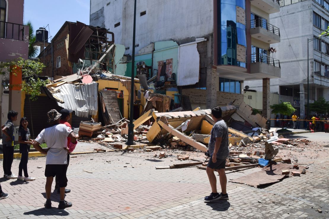 Residents look at a building that collapsed after an earthquake struck Machala, Ecuador, on March 18, 2023.
