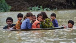 TOPSHOT - A man (L) along with a youth use a satellite dish to move children across a flooded area after heavy monsoon rainfalls in Jaffarabad district, Balochistan province, on August 26, 2022. - Heavy rain continued to pound parts of Pakistan on August 26 after the government declared an emergency to deal with monsoon flooding it said had "affected" over four million people. (Photo by Fida HUSSAIN / AFP) (Photo by FIDA HUSSAIN/AFP via Getty Images)