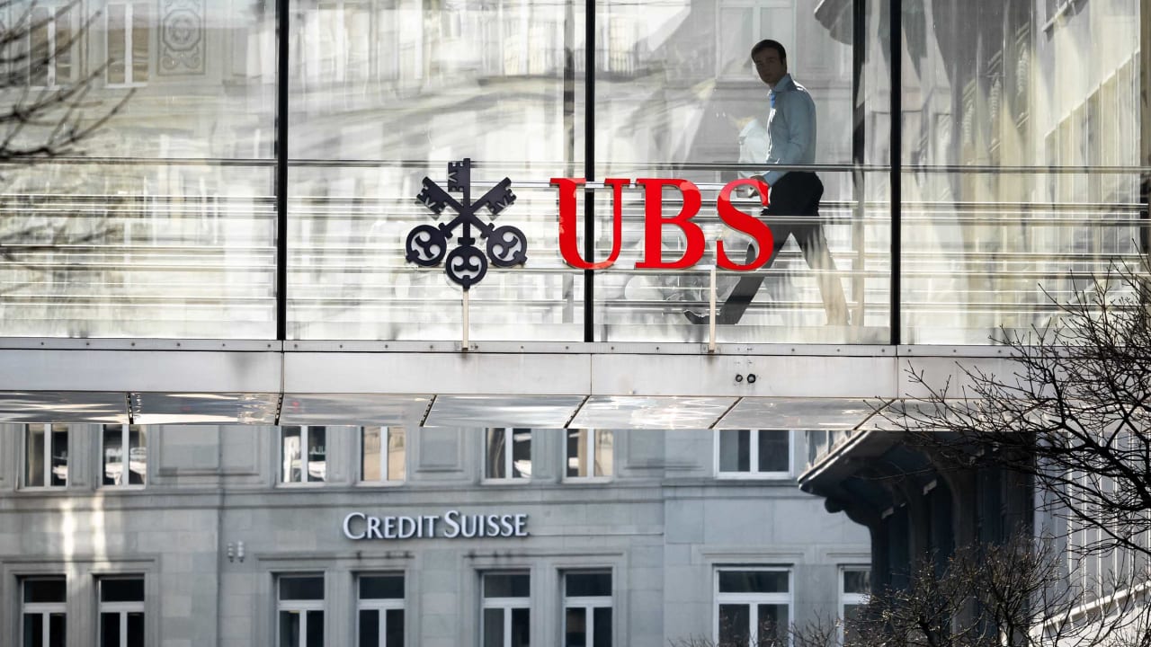 A employee is seen in silhouette next to a sign of Swiss giant banking UBS and a sign of Credit Suisse bank in Zurich on March 20, 2023. - UBS share price plunged on March 20, 2023 as a deal to take over its troubled Swiss rival Credit Suisse for $3.25 billion failed to calm stock market nerves. (Photo by Fabrice COFFRINI / AFP) (Photo by FABRICE COFFRINI/AFP via Getty Images)