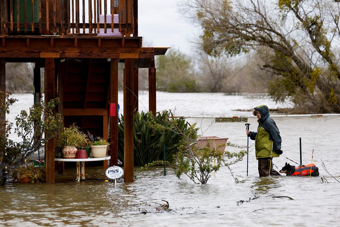 Kristen Vogt and her dog Roo walk home through floodwater Sunday in Manteca, California.