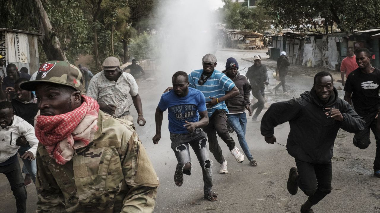 Protesters run away from water released by a police water cannon vehicle during a mass rally called by the opposition leader Raila Odinga in Kibera, Nairobi, Monday.