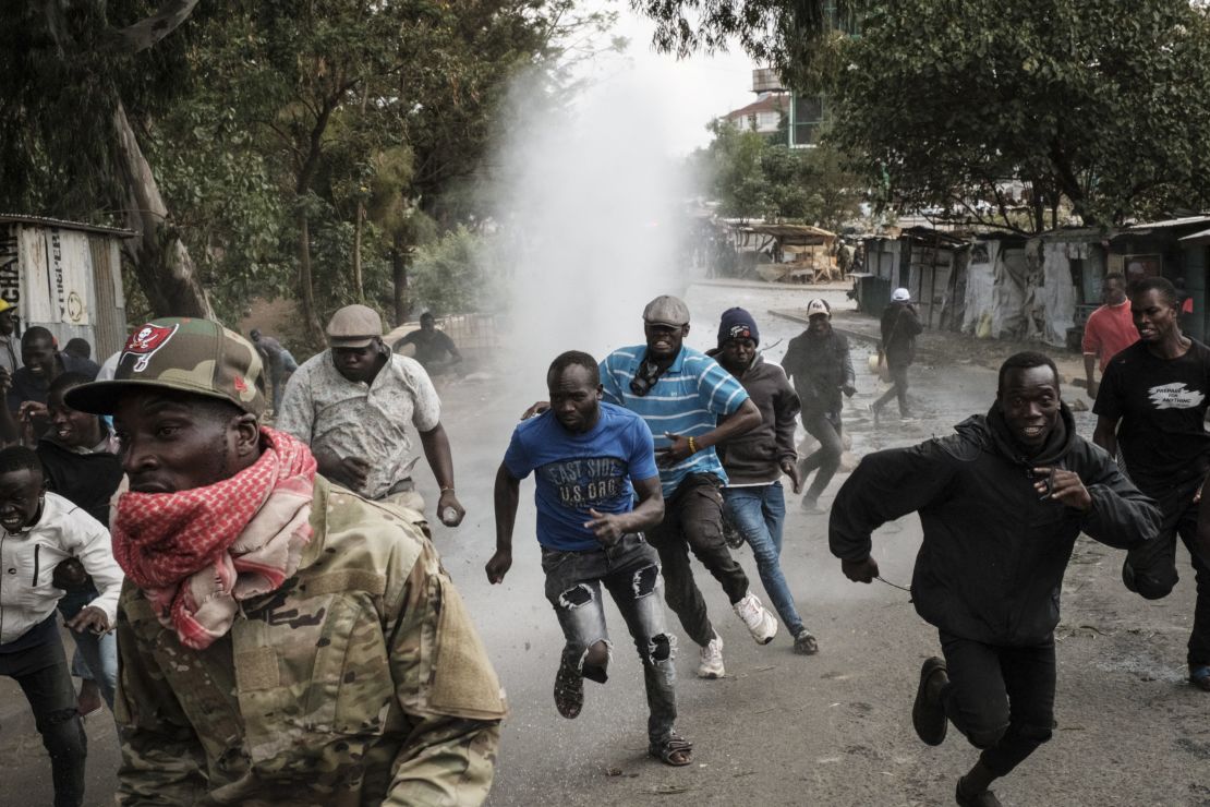 Protesters run away from water released by a police water cannon vehicle during a mass rally called by the opposition leader Raila Odinga in Kibera, Nairobi, Monday.