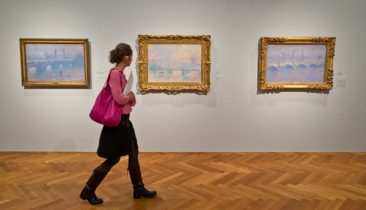 A woman walks through a Claude Monet exhibition at the Staedel Museum in Frankfurt, Germany, in 2015. Paintings (L-R): "Waterloo Bridge, Sonne," "Waterloo Bridge, Nebelmorgen" and "Charing Cross Bridge." 