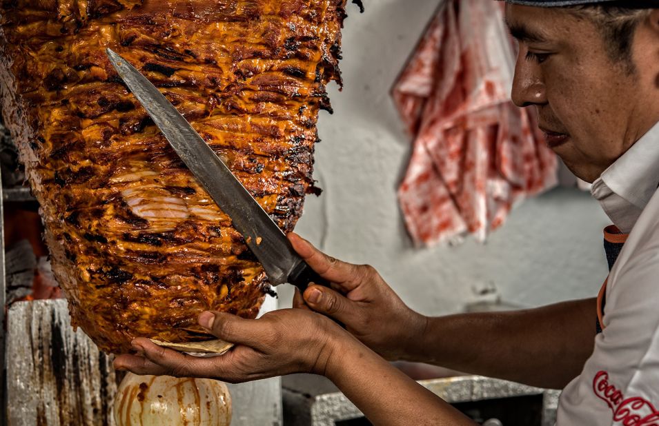 <strong>Al pastor: </strong><em>Al pastor</em> loosely translates to "shepherd-style." Here, chef Adrian Reyes cuts small slices of marinated pork cooked on a spit at El Tizoncito restaurant in Mexico City.  The meat is often served in tacos with pineapple.