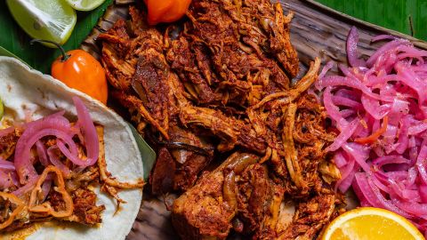 Cochinita Pibil, Mexican pit-roasted pork dish from Yucatan peninsula, served on banana leaves with traditional condiments. Tacos from Mexico.

AdobeStock_332736885