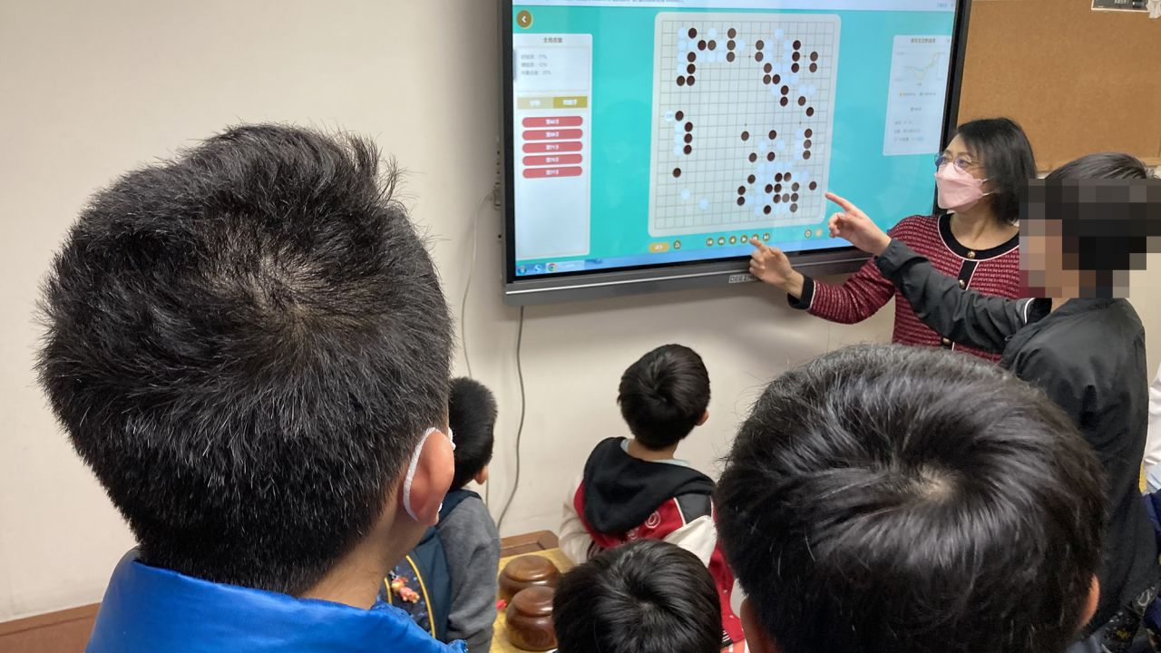 Ao Lixian and her students discuss strategy at Hong Kong Children's Go College (CNN blurred portions of the image to protect a child's identity). 
